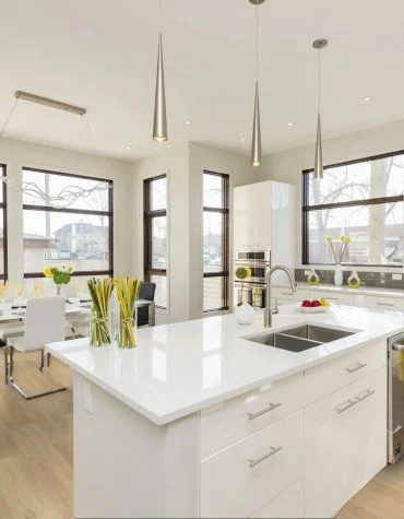 Pavimento Vinílico SPC Madeira French Oak 5.5 TRV013 instalado numa ampla cozinha de estilo contemporâneo com móveis brancos e janelas panorâmicas.