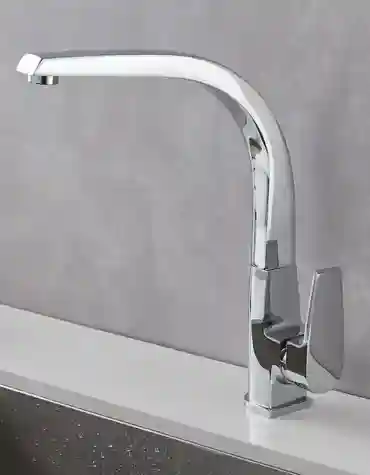 Torneira de cozinha moderna Madrid com bica curva e acabamento cromado espelhado, instalada numa bancada branca com lava-loiça em inox e fundo cinza claro.