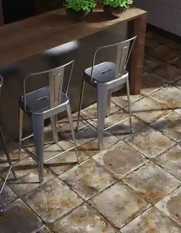 Pavimento cerâmico Rústico Certeca com aspeto desgastado, aplicado em espaço com bancada de madeira e cadeiras metálicas