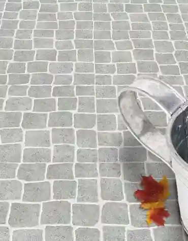 Pavimento cerâmico pedra calçada Sabugal em cor cinza, com regador metálico e folha seca