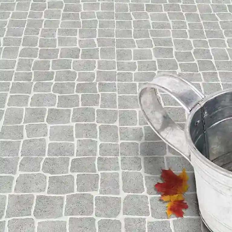 Pavimento cerâmico pedra calçada Sabugal em cor cinza, com regador metálico e folha seca