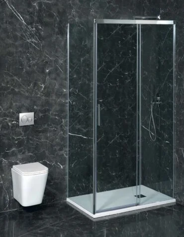 Box de duche frontal com lateral fixo Adelaide em vidro temperado e perfis slim, instalada sobre base nivelada num banheiro com revestimento escuro.