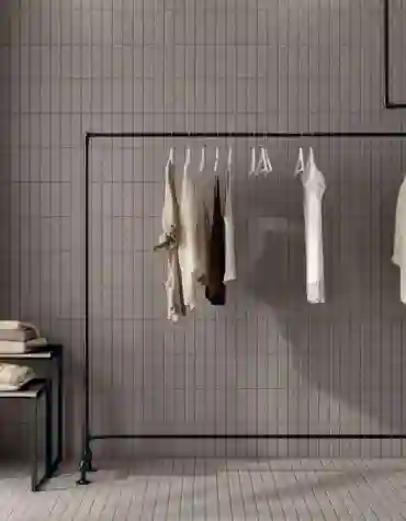 Loja contemporânea com pavimento cerâmico Naos 40x60 em tom neutro e cabideiro minimalista